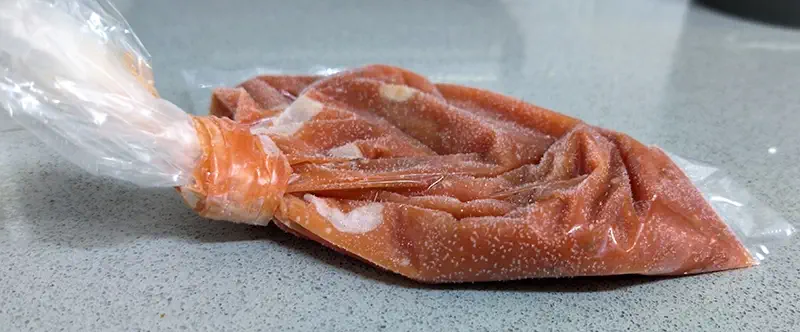 A frozen pizza tomato sauce in a sandwich bag