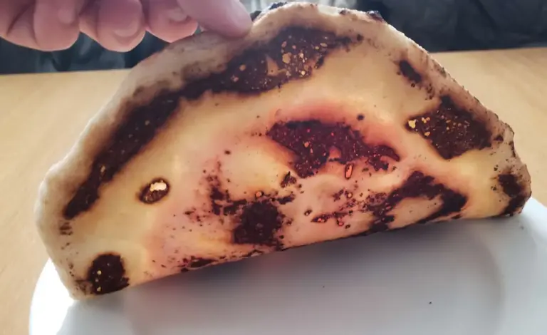 A picture of a burnt pizza bottom because of excess dusting flour