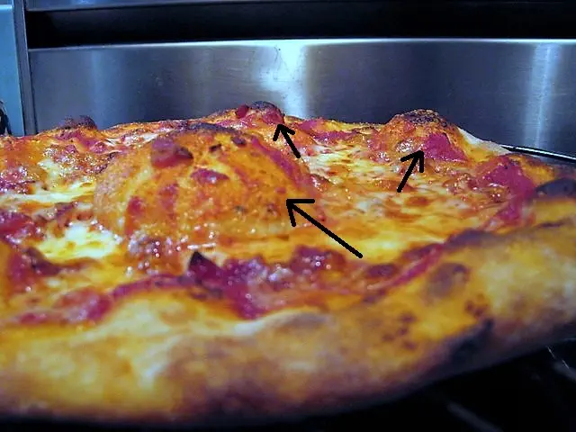 A pizza with bubbles forming at its base during baking