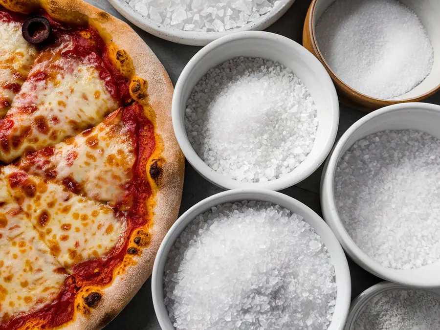 Bowls of salt next to a pizza