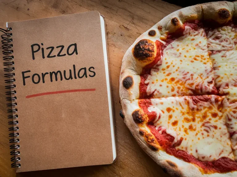 A pizza next to a notebook with a cover reading "Pizza Formulas"